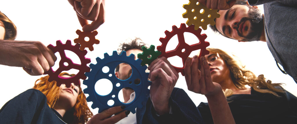 equipo de trabajo sosteniendo engranes que simbolizan estrategias para retener talento en PYMES
